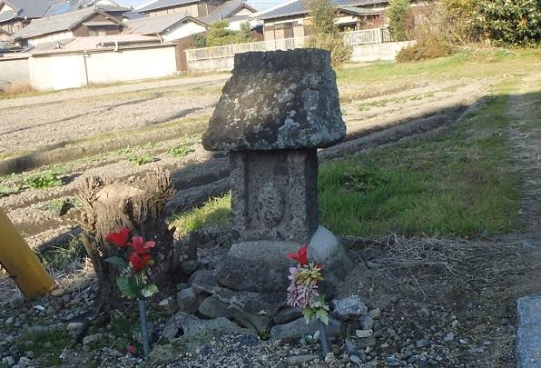田んぼの前に建立された乳神を祀る石造りの小祠に供えられた二輪の花の写真