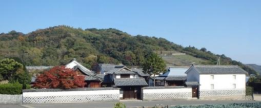 雲一つない晴天の下そびえ立つ山々を背景に建つ広大な多度津藩家老林求馬邸を遠目のアングルから撮影した写真