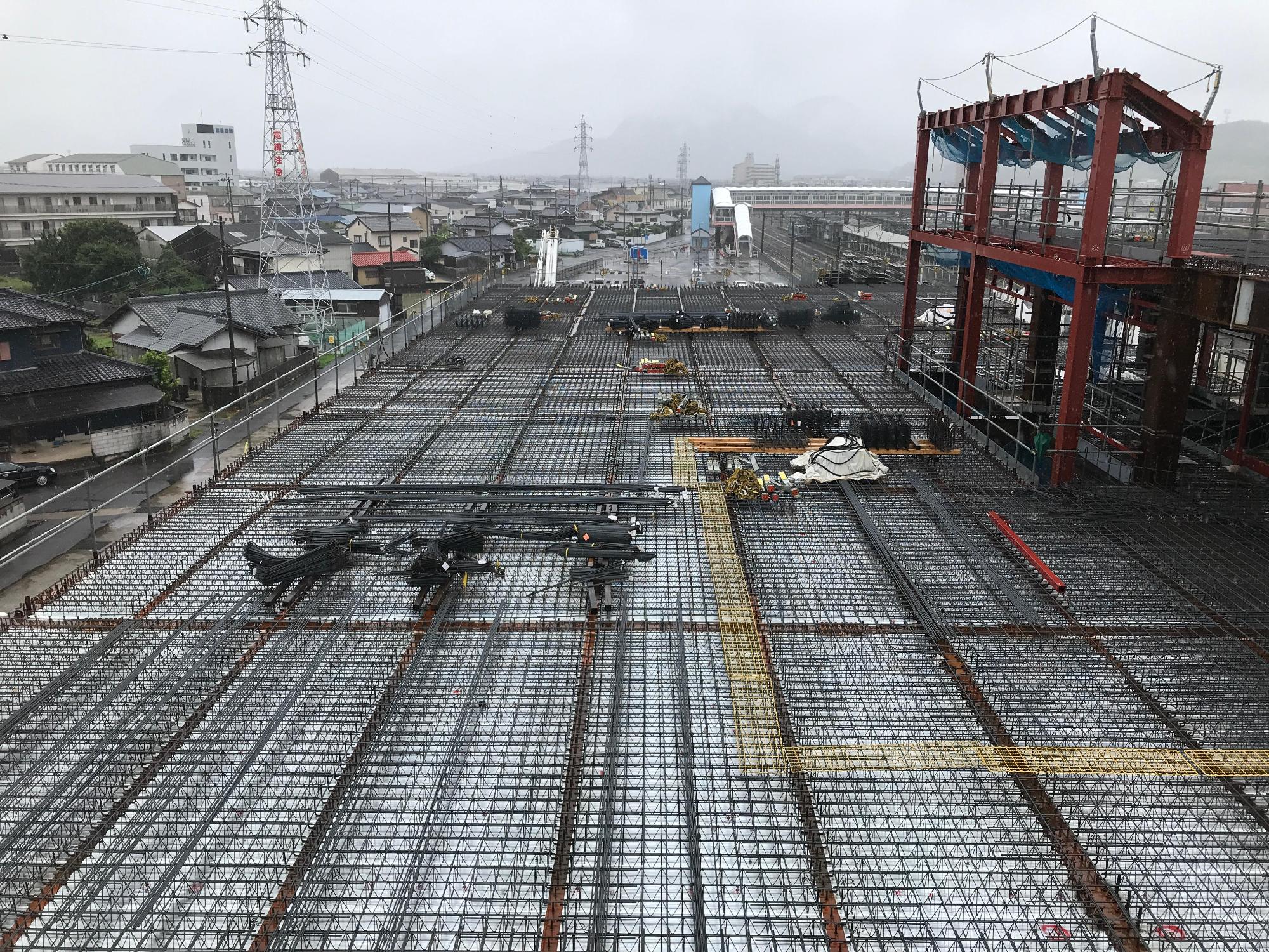 多度津町新庁舎ホール棟屋上駐車場床の一面に敷かれた骨組みを雨の中6月21日に撮影した写真