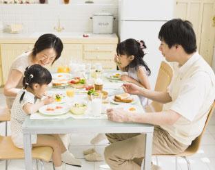 4人家族が楽しそうに食卓を囲む様子が写った写真