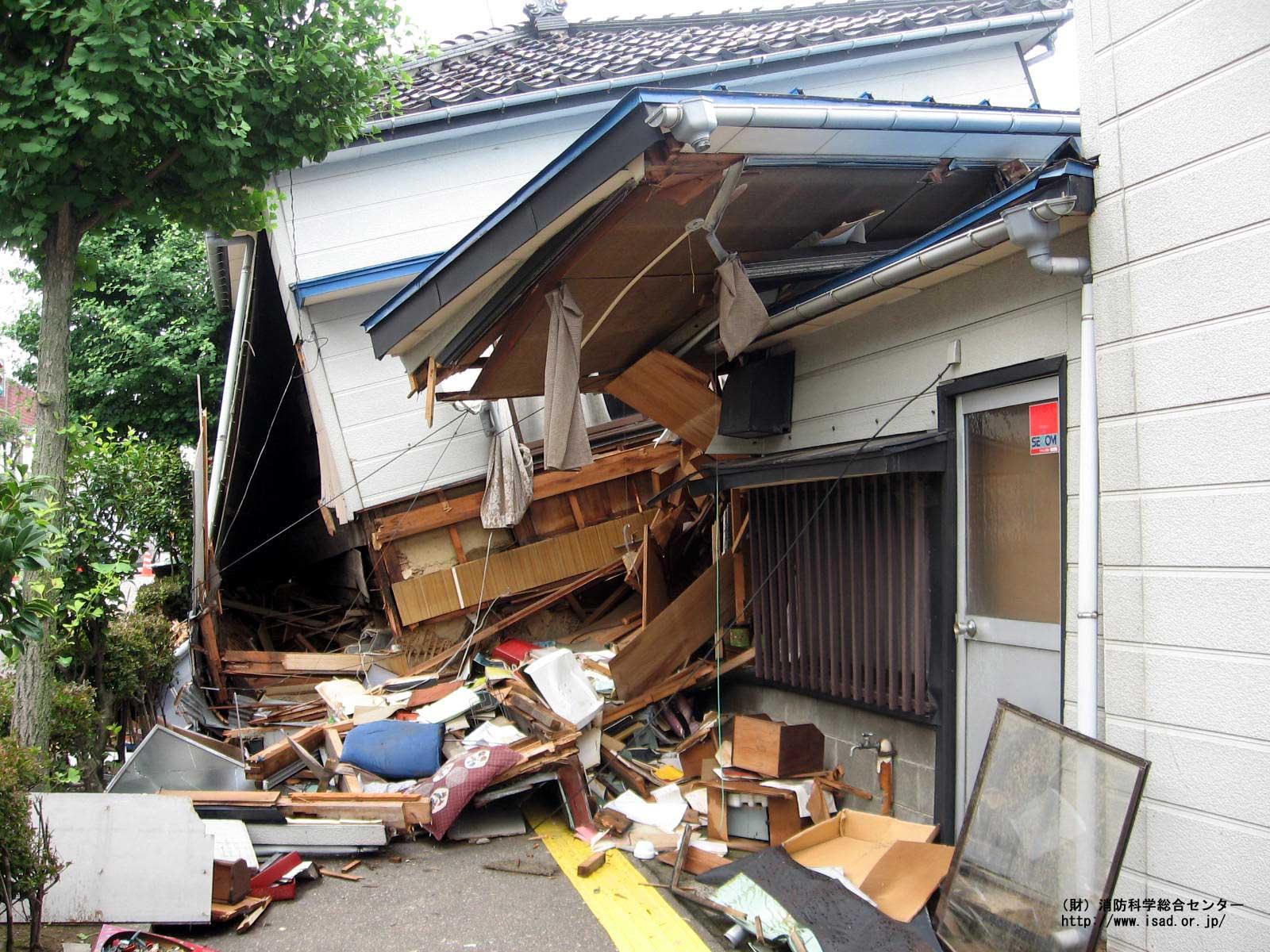 地震により1階部分が潰れ半壊した家を写した写真
